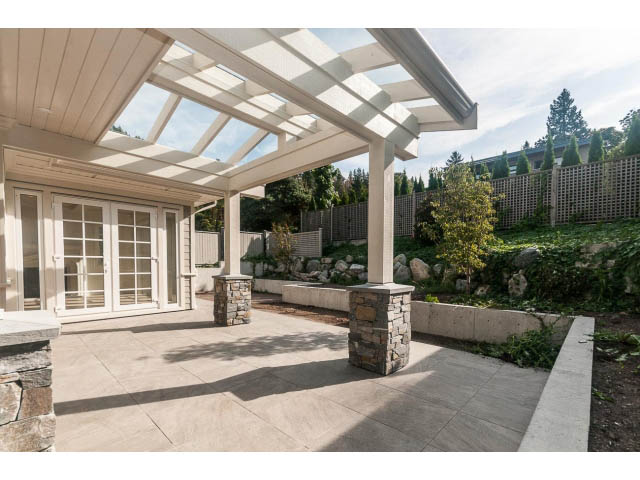 Covered patio with stone accents and greenery. - 6448 Argyle Ave, West Vancouver