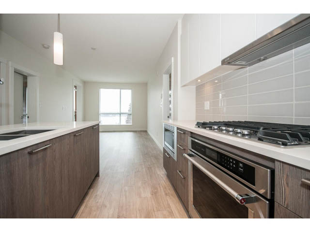 Bright kitchen with white countertops, hardwood floors, and stainless steel appliances. - 303 - 615 East 3rd Street, North Vancouver
