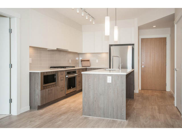 Bright kitchen with modern cabinetry, hardwood floors, and a large island. - 303 - 615 East 3rd Street, North Vancouver