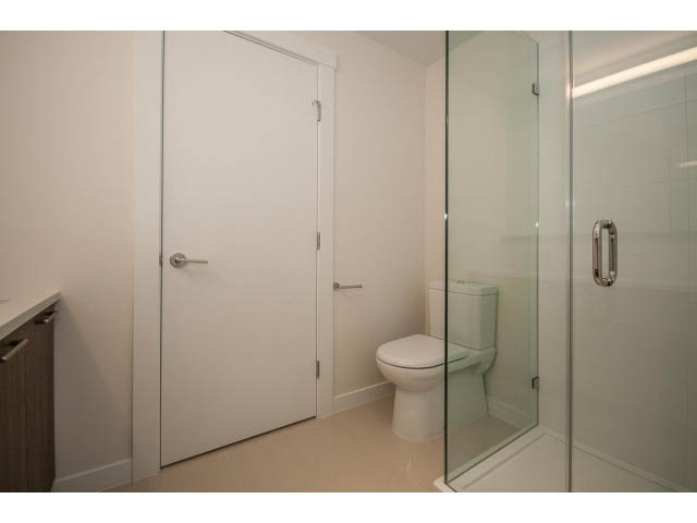 Bright bathroom with glass shower and white fixtures. - 303 - 615 East 3rd Street, North Vancouver