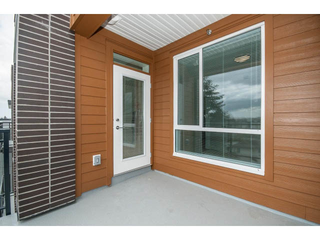 Furnished balcony with sliding glass doors and large windows, offering a view of the city skyline. - 303 - 615 East 3rd Street, North Vancouver