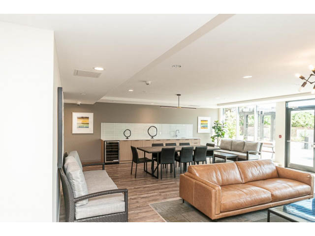 Spacious living room with leather couch, hardwood floors, and large windows. - 303 - 615 East 3rd Street, North Vancouver