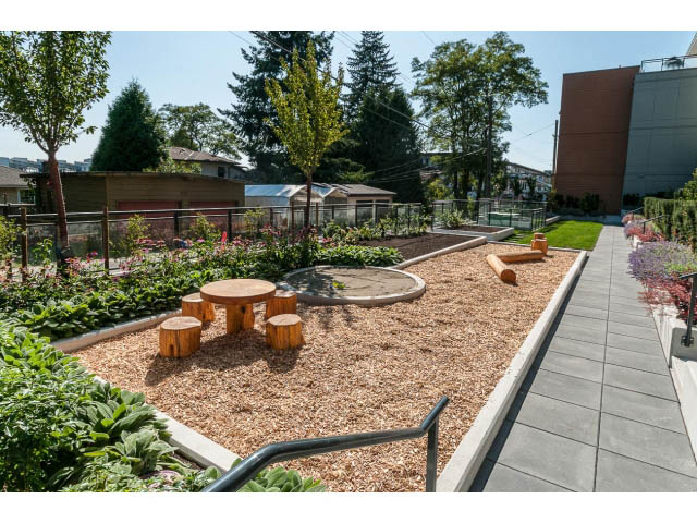 Furnished outdoor garden with wooden seating and mulch paths. - 303 - 615 East 3rd Street, North Vancouver