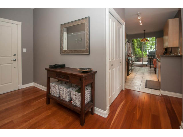 Furnished entryway with hardwood floors, wooden console table, and a view into the kitchen. - 310 - 160 E 13th St, North Vancouver