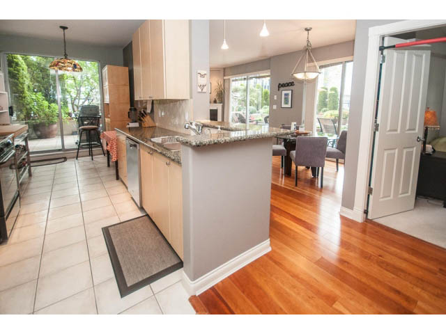 Bright kitchen with granite countertops and hardwood floors, leading to a cozy dining area. - 310 - 160 E 13th St, North Vancouver