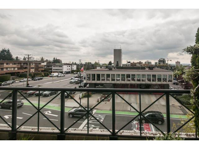 Bright balcony with city view and greenery, overlooking a bustling street scene. - 310 - 160 E 13th St, North Vancouver