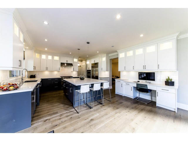 Bright kitchen with white cabinetry, hardwood floors, and a modern island. - 3075 Dryden Way, North Vancouver
