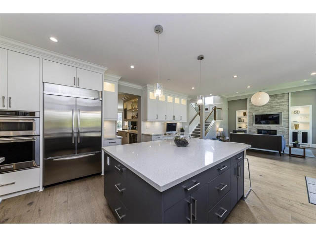 Bright kitchen with modern appliances, gray island, hardwood floors, and a city view. - 3075 Dryden Way, North Vancouver