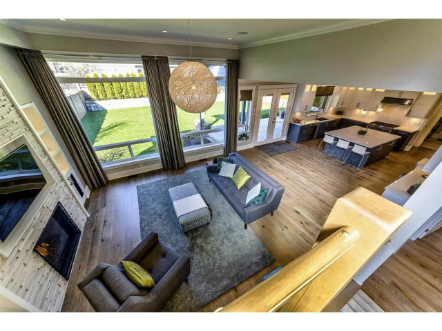 Bright living room with hardwood floors, large windows, and a cozy fireplace. - 3075 Dryden Way, North Vancouver