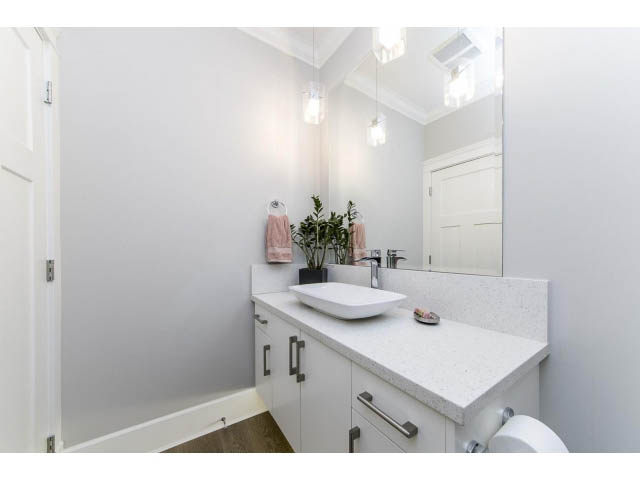 Bright bathroom with white cabinets, granite countertops, and a large mirror. - 3075 Dryden Way, North Vancouver