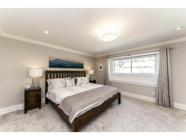 Spacious bedroom with a large bed, wooden frame, and a mountain painting above. - 3075 Dryden Way, North Vancouver