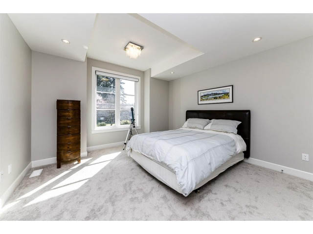 Bright master bedroom with large bed, light gray carpet, and a window with a view. - 3075 Dryden Way, North Vancouver