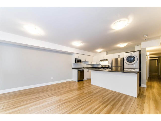 Open-concept living area with hardwood floors and modern appliances. - 3075 Dryden Way, North Vancouver
