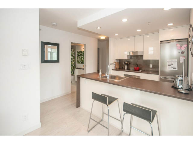 Bright kitchen with white cabinets, dark countertops, and modern bar stools. - 501 - 161 West Georgia St, Vancouver Downtown
