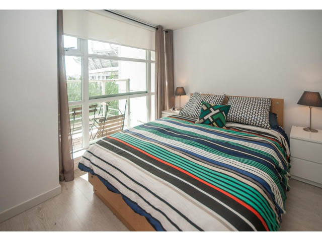 Bright bedroom with striped bedding and city view. - 501 - 161 West Georgia St, Vancouver Downtown