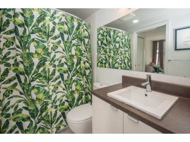 Furnished bathroom with banana leaf shower curtain and modern sink. - 501 - 161 West Georgia St, Vancouver Downtown