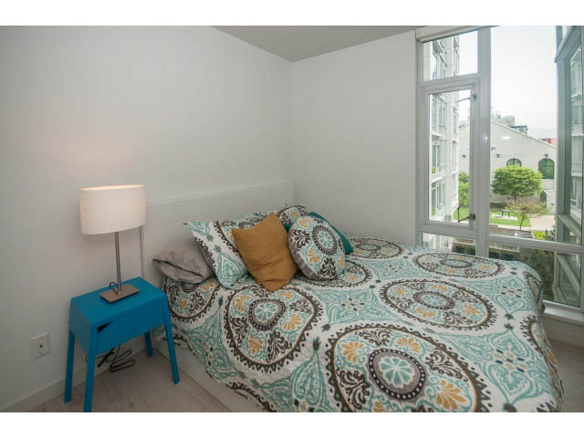 Furnished bedroom with patterned bedding and city view. - 501 - 161 West Georgia St, Vancouver Downtown