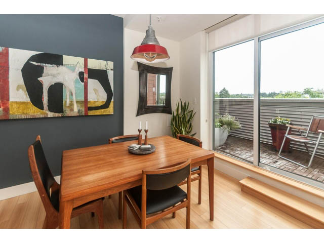 Bright dining area with wooden table, modern artwork, and city view. - 4123 - 2250 Commercial Dr, Vancouver East Side