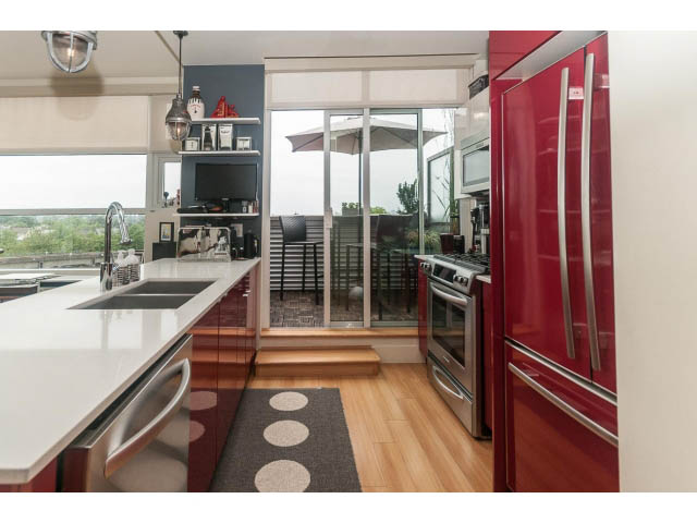 Bright kitchen with modern red appliances, hardwood floors, and city view. - 4123 - 2250 Commercial Dr, Vancouver East Side