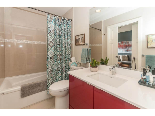 Bright bathroom with red cabinets, white countertop, and patterned shower curtain. - 4123 - 2250 Commercial Dr, Vancouver East Side