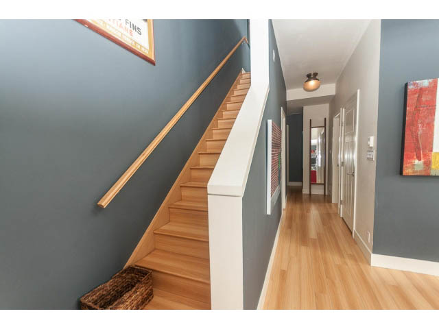 Bright hallway with wooden floors and modern decor, leading to a staircase. - 4123 - 2250 Commercial Dr, Vancouver East Side