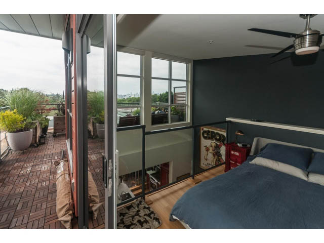 Spacious loft bedroom with large windows, hardwood floors, and a city view. - 4123 - 2250 Commercial Dr, Vancouver East Side