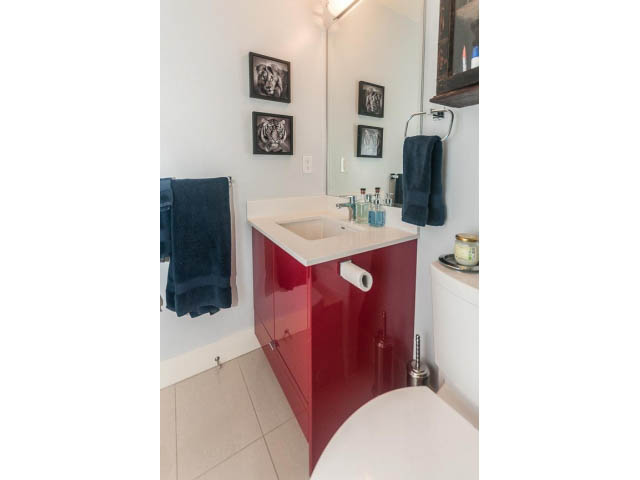 Bright bathroom with red cabinets and white countertop, neatly arranged towels and toiletries. - 4123 - 2250 Commercial Dr, Vancouver East Side