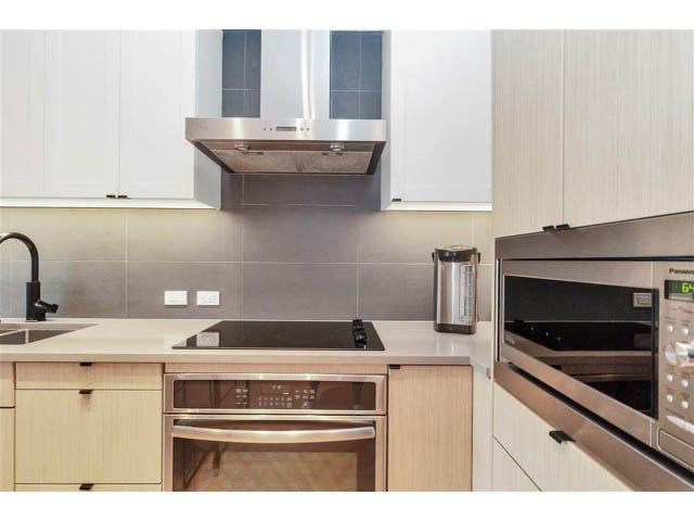 Bright kitchen with modern appliances, stainless steel counters, and a sleek design. - 305 - 3205 Mountain Highway, North Vancouver
