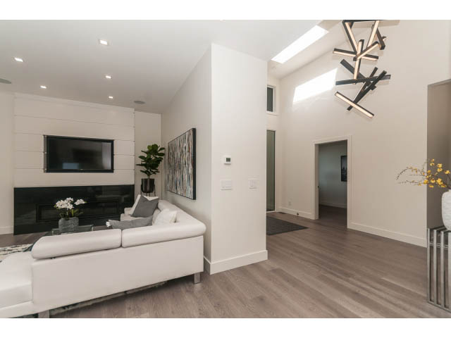 Bright living room with white furniture, hardwood floors, and a modern fireplace. - 460 Hillcrest Street, West Vancouver