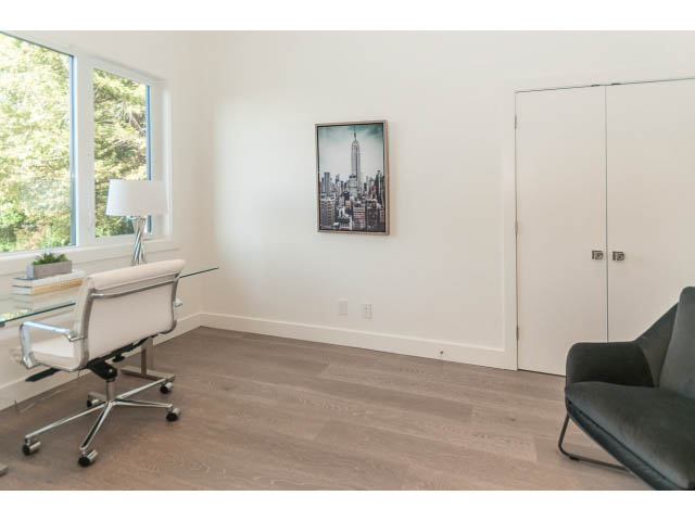 Bright living room with hardwood floors, cityscape artwork, and a modern office chair. - 460 Hillcrest Street, West Vancouver