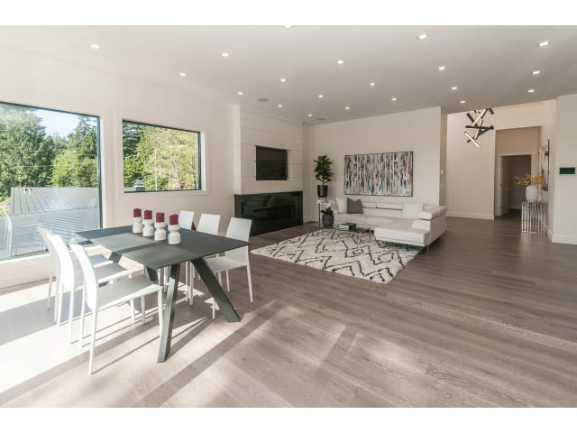 Spacious living room with hardwood floors, modern furniture, and large windows offering a view of greenery. - 460 Hillcrest Street, West Vancouver