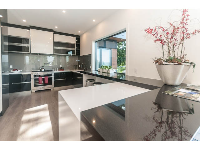 Bright kitchen with sleek black countertops, hardwood floors, and a city view. - 460 Hillcrest Street, West Vancouver