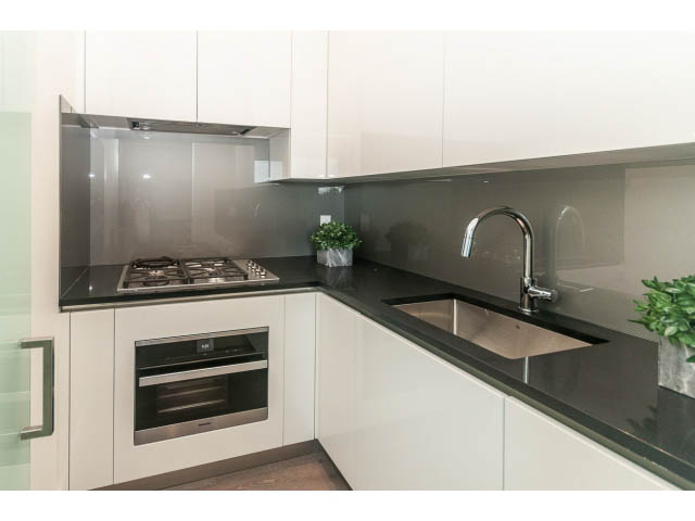 Bright kitchen with sleek white cabinets, modern black countertops, and a stainless steel backsplash. - 460 Hillcrest Street, West Vancouver