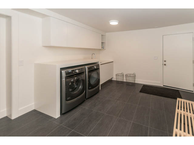 Spacious laundry room with white cabinets, dark tile flooring, and modern appliances. - 460 Hillcrest Street, West Vancouver