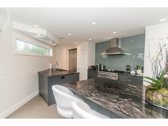 Bright kitchen with modern design, granite countertops, and a large window offering a view. - 5385 Kew Cliff Rd, West Vancouver