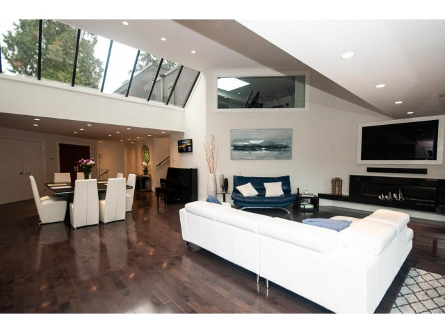 Spacious living room with hardwood floors, modern white furniture, and a large flat-screen TV. - 5385 Kew Cliff Rd, West Vancouver