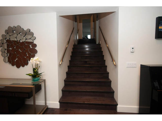 Foyer with dark wood staircase, modern decor, and a circular mirror. - 5385 Kew Cliff Rd, West Vancouver