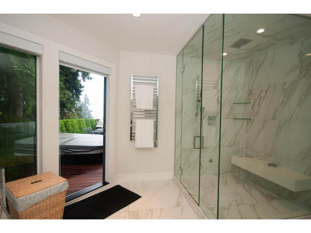 Spacious bathroom with marble walls, glass shower, and outdoor view. - 5385 Kew Cliff Rd, West Vancouver
