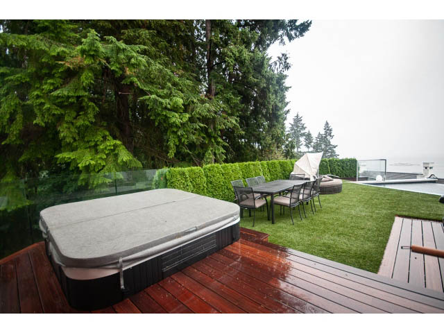 Furnished deck with hot tub, grassy lawn, and forest view. - 5385 Kew Cliff Rd, West Vancouver