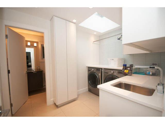 Bright kitchen with white cabinets, stainless steel sink, and a skylight above. - 5385 Kew Cliff Rd, West Vancouver