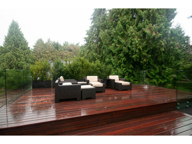 Furnished outdoor deck with wet wood flooring and lush greenery. - 5385 Kew Cliff Rd, West Vancouver