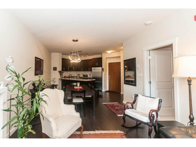 Furnished living room with hardwood floors and modern kitchen counter. - 311 - 159 West 22nd Street, North Vancouver