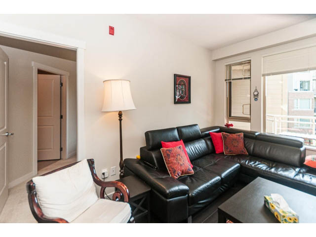 Furnished living room with black leather couch, red pillows, and city view. - 311 - 159 West 22nd Street, North Vancouver