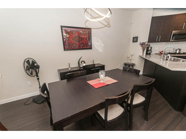 Furnished dining area with dark wood table, modern light fixture, and granite countertops. - 311 - 159 West 22nd Street, North Vancouver