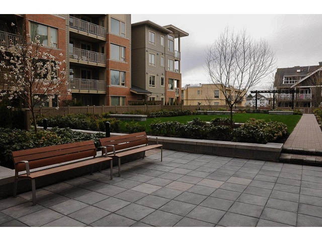 Furnished patio with benches, greenery, and apartment buildings in the background. - 311 - 159 West 22nd Street, North Vancouver
