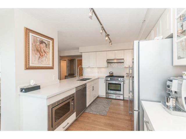 Bright kitchen with white countertops, hardwood floors, and a city view. - 2204 - 1238 Richards Street, Vancouver Downtown