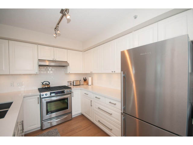 Bright kitchen with white cabinets, stainless steel appliances, and hardwood floors. - 2204 - 1238 Richards Street, Vancouver Downtown