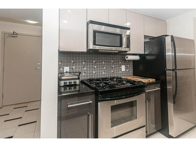 Bright kitchen with stainless steel appliances and tiled backsplash, modern and clean.