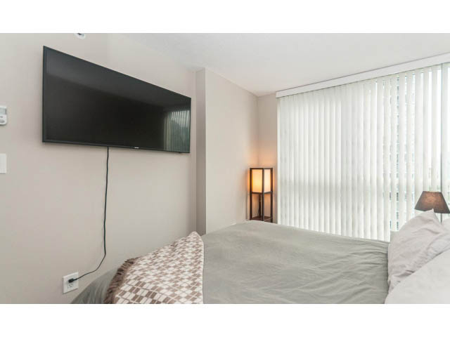 Bright bedroom with modern TV, white blinds, and cozy bedding. - 2005 - 1408 Strathmore Mews North West One, Vancouver Downtown