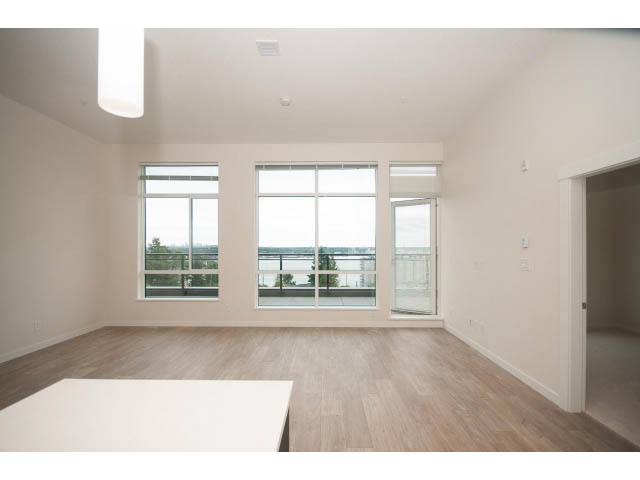 Bright living room with hardwood floors and large windows offering a city view. - 402 - 625 East 3rd Street, North Vancouver